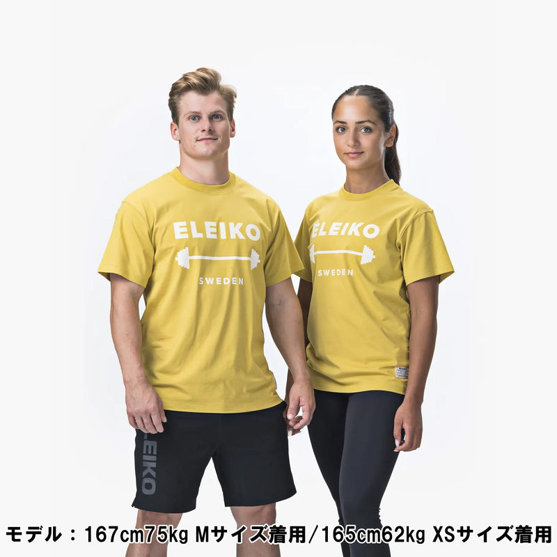 ELEIKO 1957 Tシャツ ユニセックス イエロー 女性モデル正面上半身でロゴとバーベルデザインが中央に配置された着用スタイル
