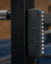 ELEIKO クリーニングブラシ ブラックをラック支柱に装着した状態を横から捉えた構図。磁石で固定された本体側面とブラシ毛の並び、ジム環境で使用する清掃用ブラシの設置状態が分かる構図
