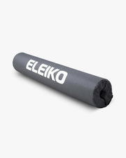 ELEIKO バーパッド ブラックを斜め上から長手方向に捉えた構図。耐久性のあるブラックカバー素材と大きなELEIKOロゴ、スクワット時の肩保護用クッション形状が確認できるバーベル用パッド