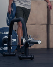 ELEIKO オープンカラー ブラックをバーベルシャフトに装着する動作を斜め横から捉えた構図。プレート横でレバー操作して固定するクイックロック機構が分かる使用シーン