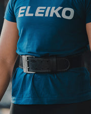 ELEIKO ウェイトリフティングレザーベルト ブラックを装着した状態でバーベルをオーバーヘッドリフトする全身後方アングル。腰部サポートとトレーニング使用シーンが分かる構図