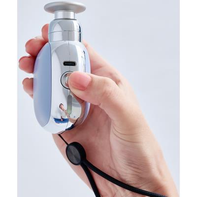 DOCTORAIR エクサガンポケット ブルーを手に持ち、側面の操作ボタンを押す様子。充電端子やストラップ、振動ヘッドを確認できる