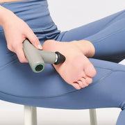 DOCTORAIR エクサガンLUXE ブラックを足裏に当てた使用例。椅子に座った状態でアタッチメントを足裏へ押し当てる様子を確認できる構成