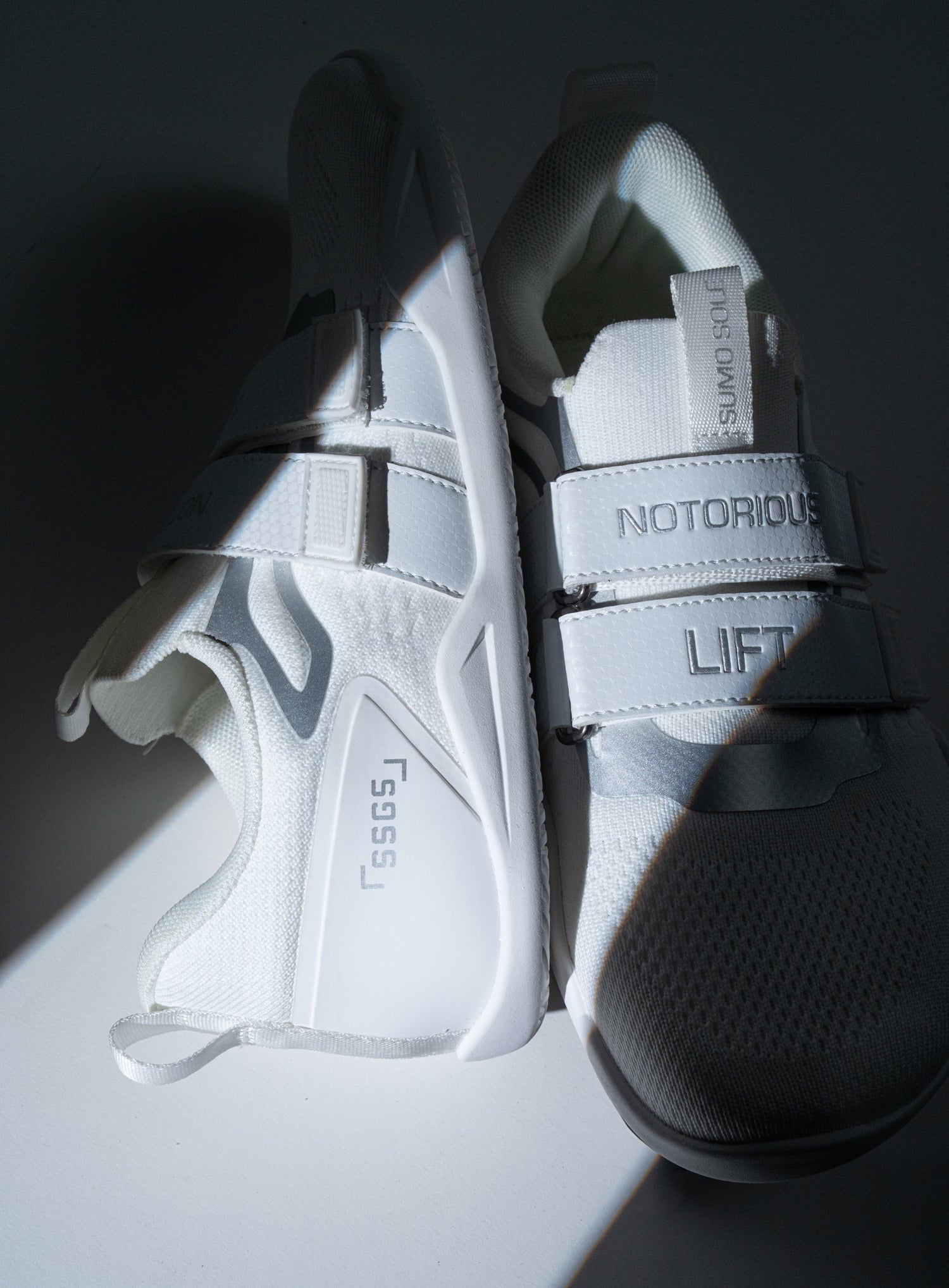 NOTORIOUS LIFT SUMO SOLE GEN5 ホワイト ベアフットシューズを上から斜め俯瞰で配置し、デュアルストラップとニットアッパー、ヒールカウンター構造が分かるトレーニングシューズディテール