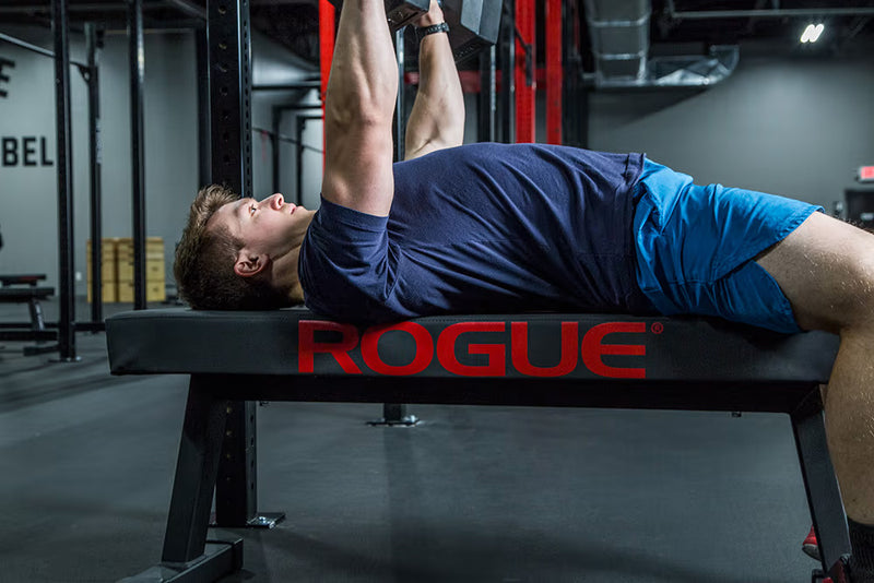 ROGUE コンペテション ファットパッド ブラックでダンベルを押し上げる動作を斜め横から撮影、肩甲骨の安定とパッド幅の広さが分かる視点