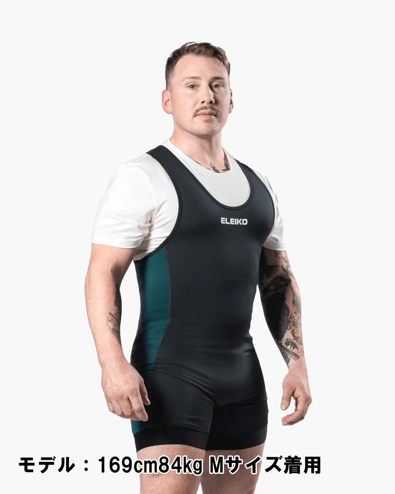 ELEIKO パワーリフティング シングレット IPF公認品 ストロングブルーを男性モデルが正面斜めから着用した全身構図。胸のELEIKOロゴとサイドのストロングブルーパネルが分かるシングレット