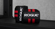 ROGUE リストラップ ブラック＆レッドをジムベンチ上で斜め前方から捉えた巻いた状態でロゴタグと立体感、使用シーンが分かる構図