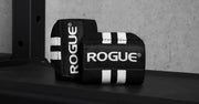 ROGUE リストラップ ブラック＆ホワイト ラック上に置いた斜め前方アングル、立て掛けた状態でロゴ面とストライプの立体感が分かる使用シーン寄り構図