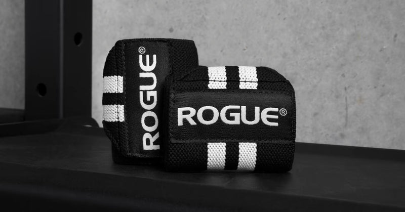 ROGUE リストラップ ブラック＆ホワイト ラック上に置いた斜め前方アングル、立て掛けた状態でロゴ面とストライプの立体感が分かる使用シーン寄り構図