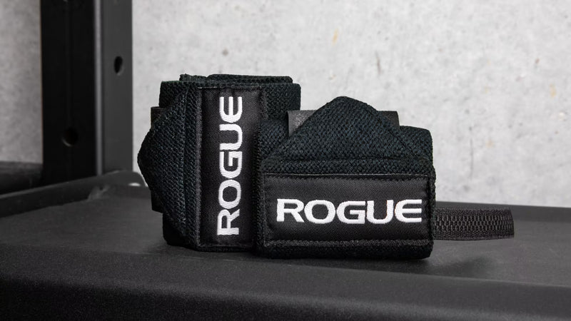 ROGUE リストラップ ネイビーブルーをジムベンチ上で斜め前方から捉えた巻いた状態でロゴタグと立体感、使用シーンが分かる構図