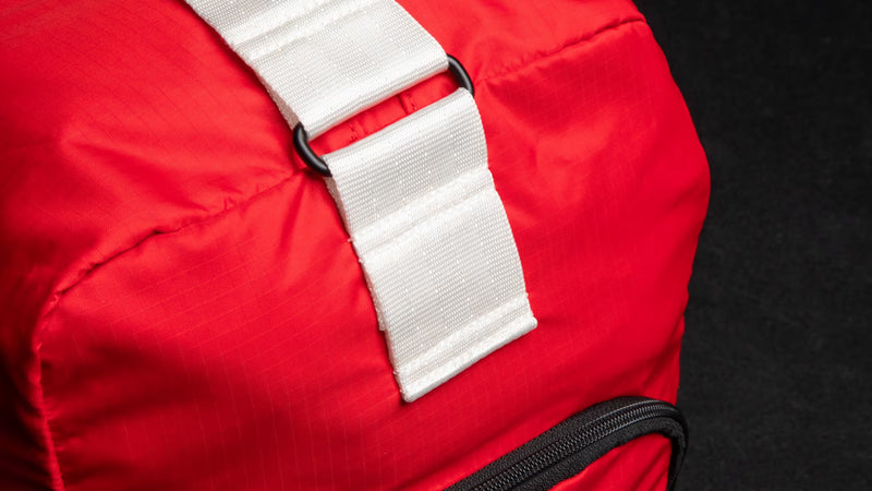 ROGUE オールドスクールジムバッグ レッド、側面ポケット部分を斜め前方から捉えた接写構図、ブラックファスナー付き外部ポケットと円筒形ボディの形状が分かる仕様