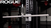 シルバーカラーのROGUE ステンレス ストレート ラットバー ケーブルアタッチメントをケーブルマシンに吊した状態を斜め前方から捉えた構図、バー全体と接続ブラケットが分かる