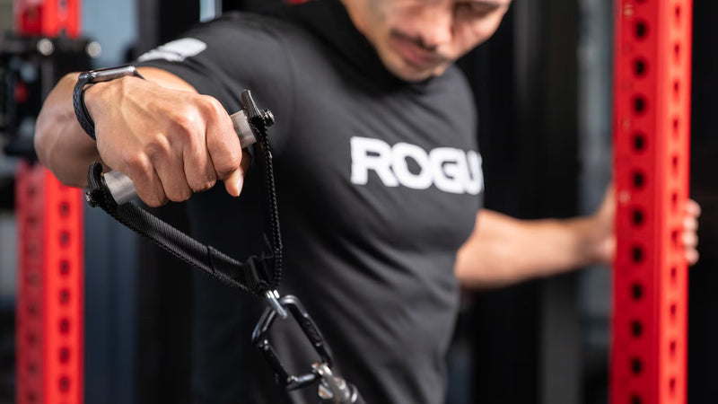 ROGUE シングルハンドル ケーブルアタッチメント ハンドル直径28.5MM シルバー ベンチに座り片手で引く動作の正面寄りビュー、ハンドル位置と肘角度が分かる使用シーン