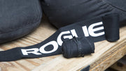 ROGUE ラップ ブラックを木製ベンチ上で斜め上から捉えた構図、巻かれたリストラップ本体と面ファスナー部分の形状が分かる配置