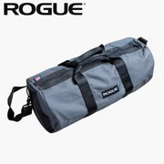 ROGUE ジムバッグ グレーを左前方から捉えた全体ビュー、円筒型ボディとブラックストラップ、前面ロゴタグ位置が分かる構図