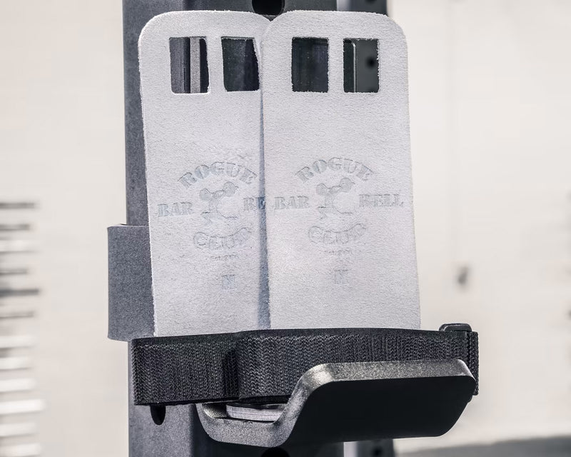ROGUE V2 ジムナスティックグリップ グレーをラックに掛けた状態を正面寄りの角度から撮影。2枚のグリップとブラックストラップ、レザー素材の表面テクスチャが分かる構図